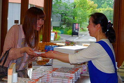 沼の家でお土産を買う女性