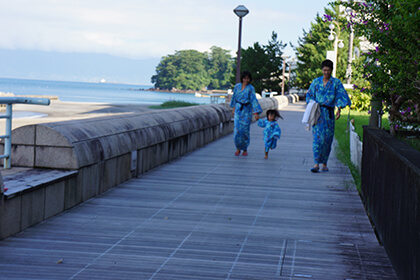 浴衣姿で海沿いを歩く家族